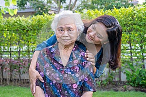 Asian elderly woman with caregiver walking with happy in nature park