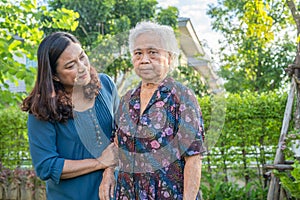 Asian elderly woman with caregiver walking with happy in nature park