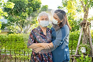 Asian elderly woman with caregiver walking with happy in nature park