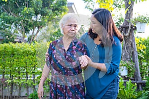 Asian elderly woman with caregiver walking with happy in nature park