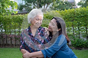 Asian elderly woman with caregiver walking with happy in nature park