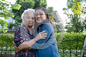 Asian elderly woman with caregiver walking with happy in nature park