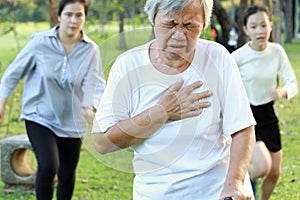 Asian elderly woman having difficulty breathing suffer from heart attack,heart problem while walking exercise at park, daughter