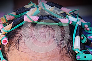 Asian elderly woman  head and colorful plastic rollers with hair perm solution , curling process background