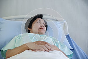 Asian elderly woman lying on bed with anxious and worried expression face at hospital photo