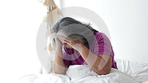 Asian elderly woman lying in bed have a headache