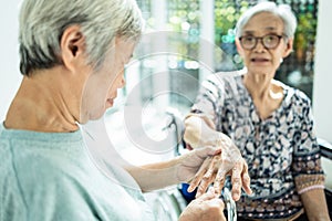 Asian elderly woman massaging palm and fingers of friend senior or sister having heumatoid arthritis, beriberi,peripheral