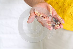 Asian Elderly woman over 70 years old holding dentures in hand. Dentures for prosthetic devices constructed to replace missing tee