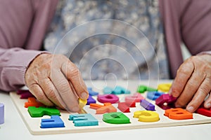 Asian elderly woman playing puzzles game to practice brain training for dementia prevention, Alzheimer disease