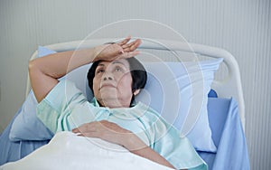 Asian elderly woman putting her hand on her forehead with anxious and stress expression face at hospital bed