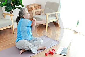 Asian elderly woman sitting at home exercising