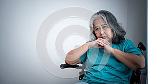 Asian elderly woman sitting in wheelchair, she is sad and anxiety from her own illness