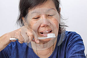 Asian elderly woman trying use toothbrush.