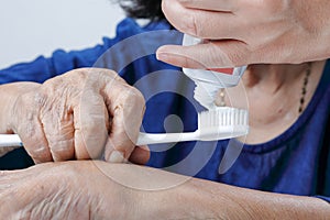 Asian elderly woman trying use toothbrush ,hand tremor.