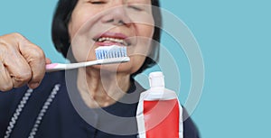 Asian elderly woman trying use toothbrush ,hand tremor . Dental health