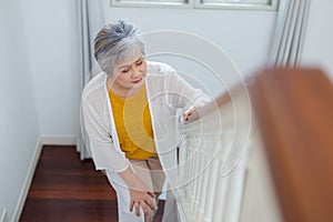 Asian elderly woman walking up stairs have pain knee ache in house. old woman went up stairs. Female old people leg pain and