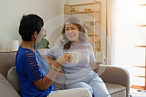 Asian elderly women talking together with friend sitting on sofa in living room at house