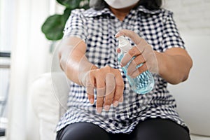 Asian elderly women wearing white masks Spray alcohol on your hands