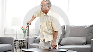 Asian Eldery senior man feeling pain in knee and standing up step walking the floor