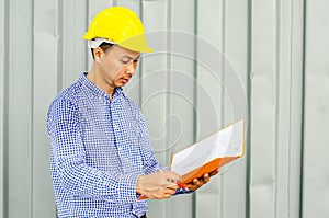 Asian Electrical Engineer holding files while wearing a personal protective equipment safety helmet