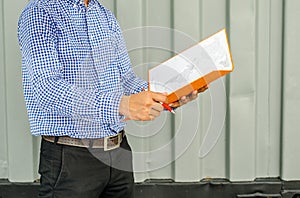 Electrical Engineer holding files while wearing a personal protective equipment safety helmet at construction site.