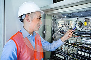 Asian Electrician at panel on construction site