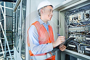 Asian Electrician at panel on construction site