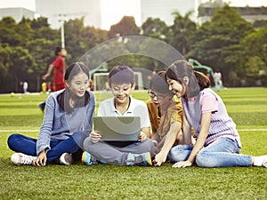 Asian elementary school children using laptop outdoors