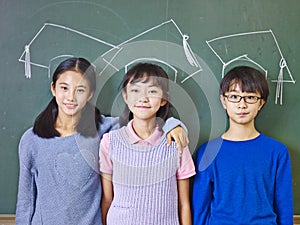 asian elementary school students standing underneath chalk-drawn doctoral hats