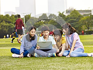 Asian elementary schoolchildren using laptop outdoors