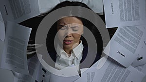 Asian employee covering herself with documents, despaired of workload, burnout