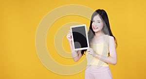 Asian employee woman showing screen tablet with blank monitor over . Cheerful asia student girl holding digital tablet