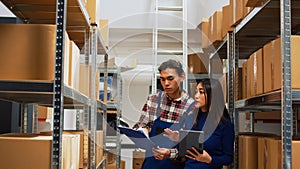 Asian employees checking warehouse supplies on tablet