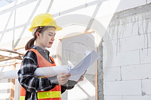 Asian engineer architect worker woman holding blueprint infrastructure progress at construction site