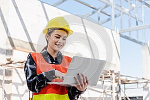 Asian engineer architect worker woman holding laptop inspect and oversee infrastructure progress at construction site