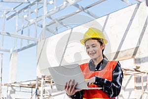 Asian engineer architect worker woman holding laptop inspect and oversee infrastructure progress at construction site