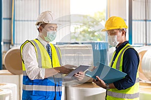 Asian engineer foreman working check list with staff worker in warehouse factory