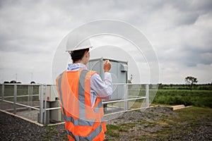 Asian engineer with hardhat using  tablet pc computer inspecting and working at wind turbine farm Power Generator Station