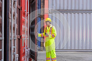 Asian engineer in helmet and uniform working on container cargo inspection at shipping yard