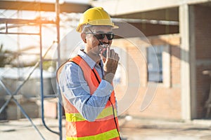 Asian engineer using radio to command to labour team in site construction