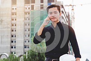 Asian engineer standing in building construction development site and calling to contractor