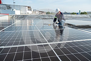 Asian engineer is using an electric meter and a laptop to check the power of solar panels on the roof of factory. Solar power or