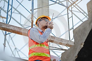Asian engineer using radio to command to labour team in site construction