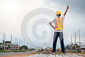 Asian engineer wearing hard hat and safety vest standing back and two thumbs up in construction site