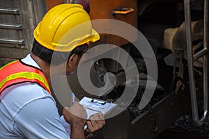 Asian engineer wearing safety helmet with checking train for maintenance in station