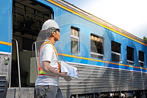 Asian engineer wearing safety helmet with checking train for maintenance in station/Engineer concept