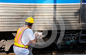 Asian engineer wearing safety helmet with checking train for maintenance in station/Engineer concept