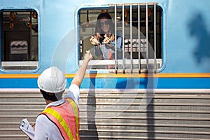 Asian engineer wearing safety helmet show mini heart to girlfriend in train