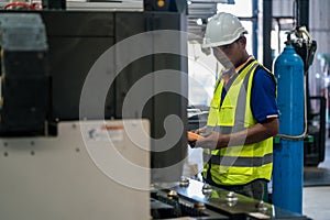 Asian engineer or worker is using remote control to control steel laser cutting machine in factory. Real worker