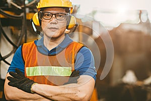 Asian engineer worker wearing earmuffs ears protection anti noise and safety suit working in factory portrait